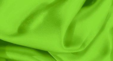 Yumuşak kıvrımlı canlı yeşil saten kumaştan bulanık, yumuşak yansımalı pürüzsüz, parlak bir yüzey yaratıyor, maddenin lüks ve ipeksi doğasını sergiliyor..