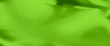 Görüntü. Karmaşık dantel dokuları olan neon yeşil kumaşın detaylı görüntüsü. Rengi pürüzsüz, dalgalı saten rengine zıt, zarif, yüksek moda bir tekstil tasarımı yaratıyor..