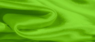 Yumuşak kıvrımlı, bulanık yeşil saten kumaş ve parlak bir yüzey ışığı nazikçe yansıtır, akıcılık ve lüks bir doku hissi yaratır..