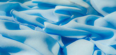 Yumuşak bir açık mavi kumaş girdabı yumuşak kıvrımlar ve pürüzsüz dokular oluşturarak yüzeyinde ince gölgeler oluşturur. Sakinleştirici tonlar ve hassas kıvrımlar sakinlik ve sükuneti çağrıştırıyor..