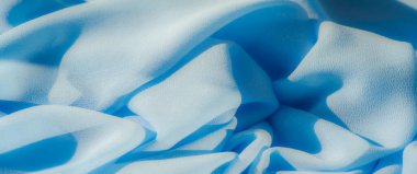 Açık mavi kumaş bulanıklığı pürüzsüz, sürekli kıvrımlar halinde akıyor. Yumuşak, kadife dokular ve akışkan hareketler ince ışıklandırmayla vurgulanır. Görüntüye derinlik ve sükunet katar..