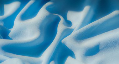 Açık mavi kumaş bulanıklığı pürüzsüz, sürekli kıvrımlar halinde akıyor. Yumuşak, kadife dokular ve akışkan hareketler ince ışıklandırmayla vurgulanır. Görüntüye derinlik ve sükunet katar..