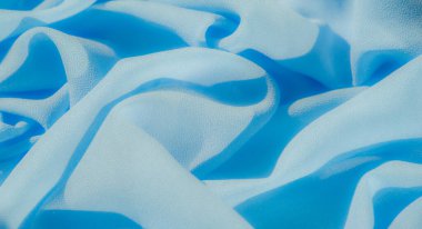 Yumuşak, açık mavi kumaş kıvrımlarını bulanıklaştırarak zarif bir doku oluşturuyor. Yumuşak tekstil rahatlatıcı bir etkiye sahiptir, hafif röfleli ve narin gölgeli minimalist bir tasarım sunar..
