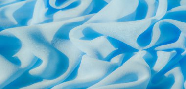 Yumuşak, açık mavi bir kumaş kıvrılır, dingin ve narin bir doku yaratır. Malzeme hafifçe akar, ışığı yansıtır, ve pürüzsüz, sakinleştirici bir tasarım hissi ekler..