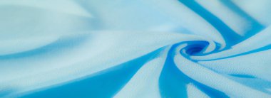 Yumuşak kıvrımları ve gölgeleri yakalayan yumuşak, açık mavi kumaş bulanıklığı. Sakin mavi ton ve narin yüzey sakin ve sofistike bir estetiği davet ediyor..