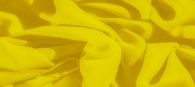 Görüntü, sarı kumaştan oluşan yumuşak ve narin bir düzendir. Soyut bir ışık ve gölge deseni oluşturur. Canlı renk ve pürüzsüz doku akış tasarımına derinlik ekler.