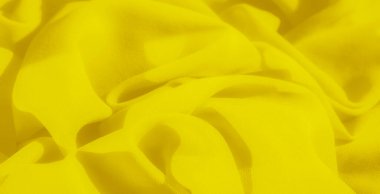 Pürüzsüz ve canlı sarı bir kumaş ve ince kıvrımlar soyut bir desen oluşturur. Sıcak ton ve akışkan tasarım görüntüye sanatsal ve dinamik bir hava katar..