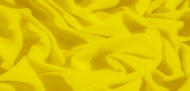 Yumuşak dalgalarda katlanmış parlak sarı kumaş bulanıklığı ışığı ve gölgeyi yakalayan dinamik bir doku yaratıyor. Kumaşların canlı renkleri pürüzsüz ve akıcı bir şekilde sergilenir..