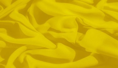 Nazik kıvrımları ve kıvrımları olan bulanık sarı kumaş dinamik ama barışçıl bir görünüm yaratır. Işık ve gölge oyunu, materyalin yumuşak dokusunu güçlendirir. Sıcak ve canlı bir ruh hali uyandırır..