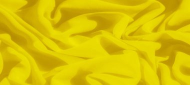 Parlak sarı kumaştan oluşan bulanık kıvrımlar yumuşak dalgalar ve doku oluşturarak canlı ve enerjik bir görsel etki yaratıyor. Yumuşak, akışkan kıvrımlar kompozisyona bir hareket ve akıcılık hissi ekler.