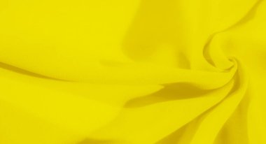 Sarı kumaş bulanıklığı yumuşak kıvrımlar halinde kıvrılarak akışkan bir doku oluşturuyor. Kumaşlar parlak renk ve pürüzsüz doku soyut ama rahatlatıcı bir görsel deneyim sunar..