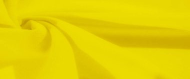 Sarı kumaş bulanıklığı yumuşak kıvrımlar halinde kıvrılarak akışkan bir doku oluşturuyor. Kumaşlar parlak renk ve pürüzsüz doku soyut ama rahatlatıcı bir görsel deneyim sunar..