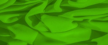 Görüntü. Pürüzsüz kıvrımları ve yumuşak dokusu olan canlı bir yeşil kumaş, nazik ve akıcı bir görünüm yaratıyor. Zengin, neon benzeri yeşil renk kompozisyona hakim.