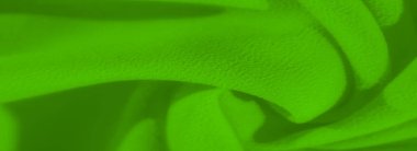 Pürüzsüz kıvrımlı canlı yeşil kumaşın bulanık görüntüsü. Yakın çekim kumaşın karmaşık dokusunu ve zarif kıvrımlarını yakalar, akıcılık ve yumuşaklık hissi yaratır..