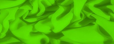 Parlak yeşil desenli sıvı ve organik katlarla sıralanmış kumaş bulanıklığı. Doğal örtüler kumaşların zengin yüzey dokusunu sergiliyor, sanatsal ve canlı bir görsel etki yaratıyor..