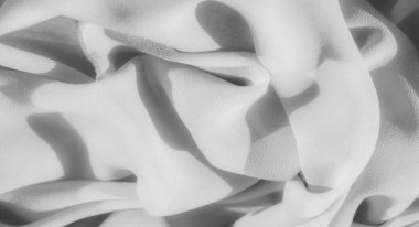 Yumuşak, akan kıvrımlarla kaplanmış gri pullu kumaş bulanıklığı. Işık ve gölge yüzeyde oynar, kumaşın zarif dokusunu vurgular ve sakin, soyut bir görsel yaratır..