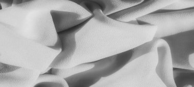 Yumuşak, akan kıvrımlarla kaplanmış gri pullu kumaş bulanıklığı. Işık ve gölge yüzeyde oynar, kumaşın zarif dokusunu vurgular ve sakin, soyut bir görsel yaratır..