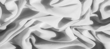 Karmaşık kıvrımları ve ince dokuları olan yumuşak gri pullu kumaş, yumuşak gölgeler bırakıyor ve maddenin pürüzsüz ve akışkan yapısını arttıran gölgeler oluşturuyor..