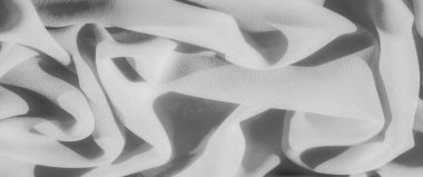 Karmaşık kıvrımları ve ince dokuları olan yumuşak gri pullu kumaş, yumuşak gölgeler bırakıyor ve maddenin pürüzsüz ve akışkan yapısını arttıran gölgeler oluşturuyor..