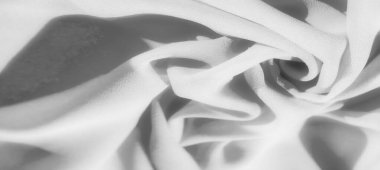 Bulanık, dalgalı gri kumaş yumuşak, kıvrımlı. Maddenin dokusu, ışık ve gölgeyle eşleştirildiğinde, minimalist bir tasarımda akıcılık ve hareket hissi yaratır..