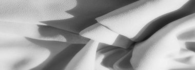 Yumuşak, gölgeli kırışıklıkları olan gri kumaştan ince kıvrımlar. İnce dokunun üzerindeki ışık etkileşimi ince bir derinlik yaratır, pürüzsüz, akıcı estetiği güçlendirir..