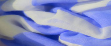İnce kıvrımlı ve hassas dokusu olan saf mavi ve beyaz kumaşın bulanık görüntüsü. Kumaştaki ışığın etkileşimi, maddenin yumuşak ve akışkan doğasını vurgular.