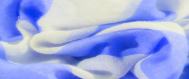 Yumuşak kıvrımlı mavi ve beyaz kumaşın bulanık görüntüsü, değişen yarı şeffaf renklerle pürüzsüz bir dokuyu gösteriyor. Kumaşlar hafif ve havadar görünümü soyut ve rahatlatıcı bir estetik yaratıyor.