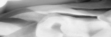 Yumuşak kıvrımlı beyaz kumaş bulanıklığı yumuşaklığını ve akışkan doğasını vurguluyor. Katmanlar ve pürüzsüz çizgiler zarif ve narin bir görünüm yaratır..