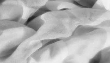 Dalgalı bir dokusu ve ışık kontrastı olan bulanık gri kumaş soyut bir tasarım yaratıyor. Karmaşık kıvrımlar derinlik ve zarafet ekler, tekstilin nazik görünümünü arttırır..