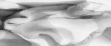 Gri tonlu bulanık kumaş, hareket ve zarafet hissi yaratan yumuşak, havadar kıvrımlar. Yumuşak şeffaflık katmanlı kumaşa hassas bir dokunuş ekler..