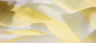 Yumuşak dalgalar ve ışık etkileşimi ile pürüzsüz sarı ve beyaz kumaş bulanıklığı sakin bir atmosfer yaratıyor. Kumaşın yumuşak dokusu ve zarif kıvrımları huzurlu ve huzurlu bir hissi yansıtıyor.