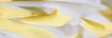 Yumuşak sarı ve beyaz kumaştan bulanık, yumuşak, akıcı bir dokuyla nazikçe katlanmış. Kumaş ışığı yakalıyor, havasını vurguluyor, narin bir his..