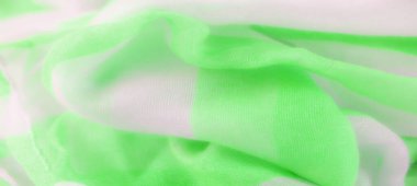 Hassas, açık yeşil ve beyaz kumaşlar birbirine dolanmış, pürüzsüz, akışkan desenler oluşturuyorlar. Renklerin yumuşak dokusu ve kusursuz karışımı dinamik bir tekstil tasarımı yaratır.