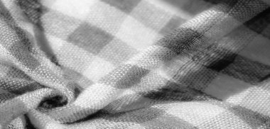 Görüntü. Ayrıntılı kıvrımları ve desenli dokuması olan gri ve beyaz kareli kumaştan yakın çekim. Yumuşak madde ve ışık ve gölgenin etkileşimi dinamik bir bileşim yaratır.,
