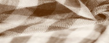 Detaylı dokuma desenli damalı bej kumaşın bulanık görüntüsü. Kumaş doğal olarak bükülür ve kıvrılır, yumuşak gölgeler bırakır ve yüzeyine ışık tutar, derinliği arttırır..