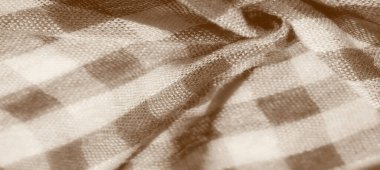 Sıcak sepya tonlarında damalı kumaş deseni olan katlanmış bulanık kumaş. Yumuşak doku ve ince ışık yansıması kumaşın hem rahat hem de sıcak bir görünüm oluşturur.
