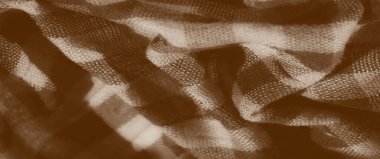 Yakın çekim kumaş görüntüsü, bej ve kahverengi yumuşak, kareli desenli. Doku, sıcacık estetiği geliştiren dokunmuş detaylarla bir sıcaklık hissi yaratıyor..