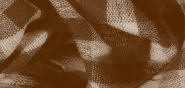 Sepya tonlarında damalı desenli kumaş bulanıklığı. Karmaşık bir şekilde katlanarak spiral bir şekle bürünmüş. Açık ve koyu gölgelerin birleşimi derinlik ve yumuşak odak yaratır.