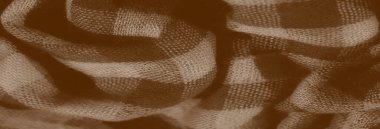 Görüntü bulanık, sepia tonlarında desenli, kareli kumaş. Karmaşık dokuma ve yumuşak örtü kumaşın yumuşak kıvrımlarında gölgelerin oynadığı klasik, kırsal bir görünüm yaratır..