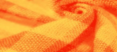 Bulanık turuncu ve sarı kumaşlı yumuşak desenli katlar. Sıcak, canlı renkler ve dokuma desenler döşeme, moda veya ev dekorasyonu projeleri için mükemmel bir ortam yaratıyor..