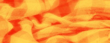 Canlı turuncu ve kırmızı kareli kumaşın bulanık görüntüsü yumuşak katlar ve dokular sergiliyor. Yüksek çözünürlüklü detaylar karmaşık dokuma ve renk karşıtlığını vurgular.