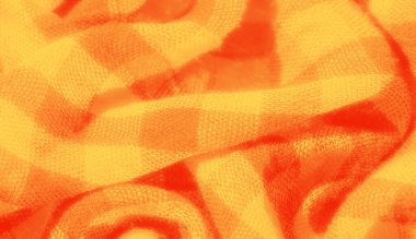 Yumuşak kıvrımlı ve dokulu yüzeyi olan sarı ve turuncu kareli kumaşın yakın çekim görüntüsü. Kumaşın sıcak tonları ve karmaşık dokuması tekstil için ideal canlı ve dinamik bir görünüm yaratır.