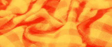 Kıvrımları ve yumuşak lifleri gösteren kırmızı kareli, dokulu turuncu kumaşın bulanık görüntüsü. Yüksek çözünürlüklü doku karmaşık dokuma ve canlı renk karşıtlığını ortaya çıkarır.