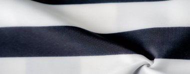 Pürüzsüz kıvrımları ve yumuşak dokuları olan bulanık siyah beyaz çizgili kumaş kalın çizgiler ve pürüzsüz kumaş arasında dinamik bir kontrastlık yaratır. Soyut düzenleme kumaşın zarafetini arttırır.