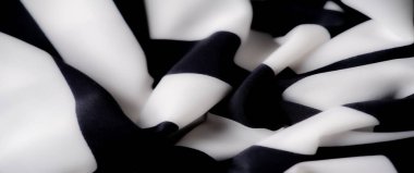 Yakın odak noktasında siyah beyaz çizgili kumaş bulanıklığı, nazik dalgalar ve akan kıvrımlar sergiliyor. Parlak dokusu ve iki ton arasındaki keskin kontrastı modern ve zarif bir görünüm yaratıyor.