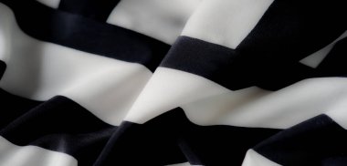 Yumuşak, dalgalı kıvrımlı ve çarpıcı çizgili siyah beyaz kumaş bulanıklığı. Aydınlık ve karanlık arasındaki zıtlık görsel olarak büyüleyici bir doku ve zarif bir hareket yaratır..