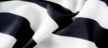 Pürüzsüz, kıvrımlı şekiller yaratmak için zarifçe katlanmış kalın çizgili lüks siyah beyaz kumaş. Keskin kontrast kumaşın pürüzsüz dokusunu ve zarif örtüsünü vurgular.