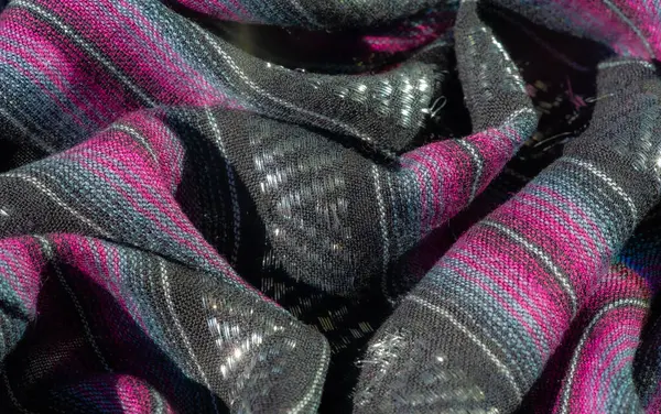 Pembe ve mor çizgilerle dokunmuş siyah bir kumaşın bulanıklığı, lüks ve sanatsal bir görünümü çağrıştıran parıltılı röflelerle dolu zengin bir doku yaratıyor..