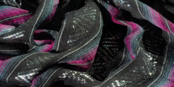 Zıt pembe ve mavi çizgili siyah kumaşlar örülmüş metalik aksanlı ayrıntılı işçilik sergiliyor. Yumuşak doku ve kıvrımlar zarif ve dinamik bir görsel oluşturur.