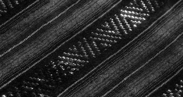 Karmaşık dokuma desenlerine yakın çekim odaklı bulanık siyah beyaz kumaş. Parlak iplikler üzerindeki ışık oyunu ve geometrik düzenleme derinlik ekler